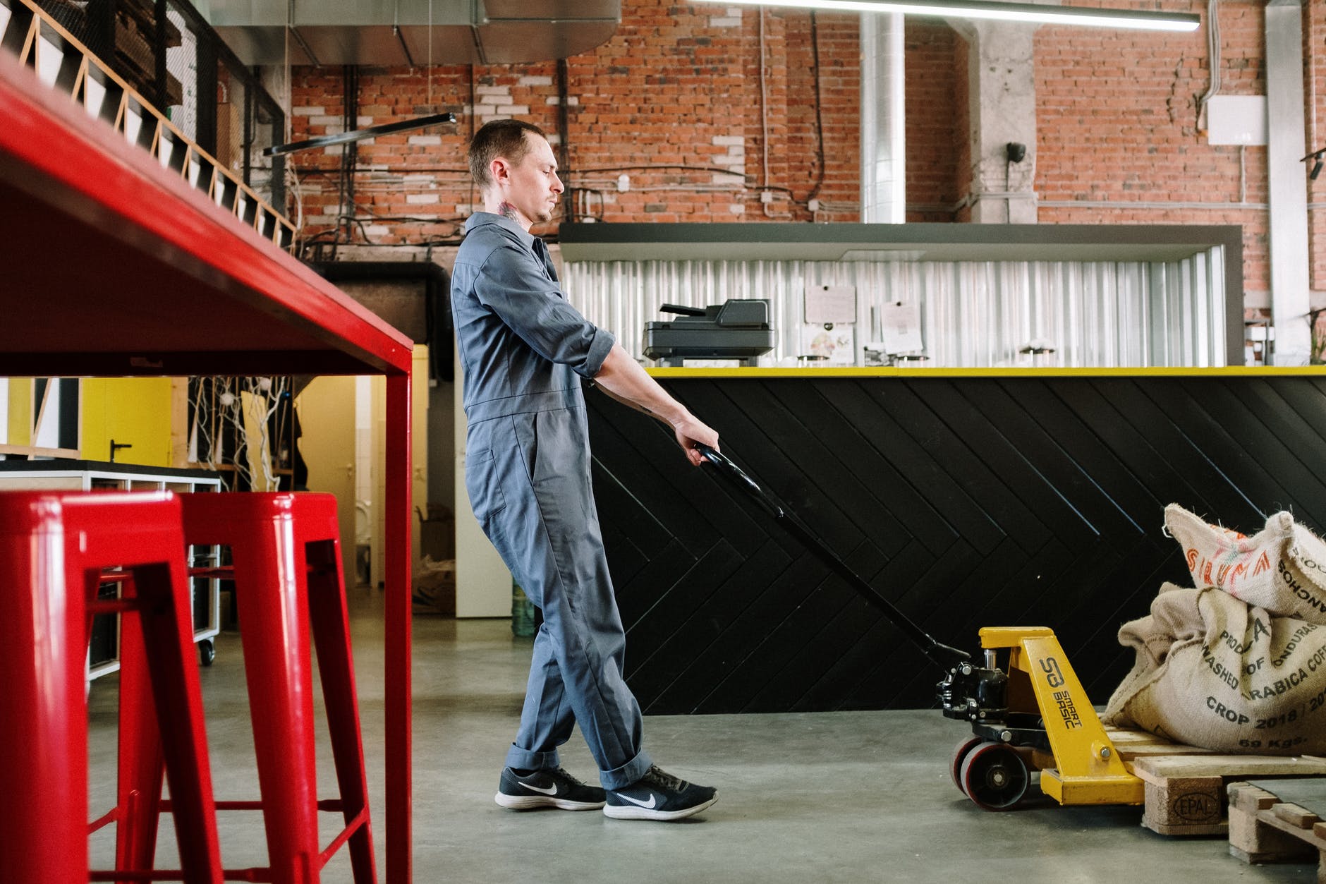 man in blue denim jacket and blue denim jeans holding black and yellow hand truck