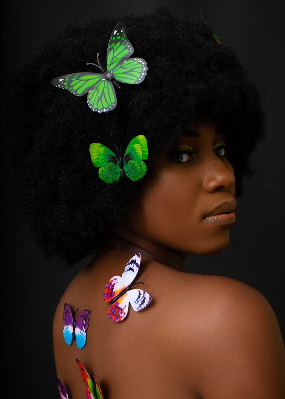 black woman with afro hairstyle and bare skin with butterflies smart money bro