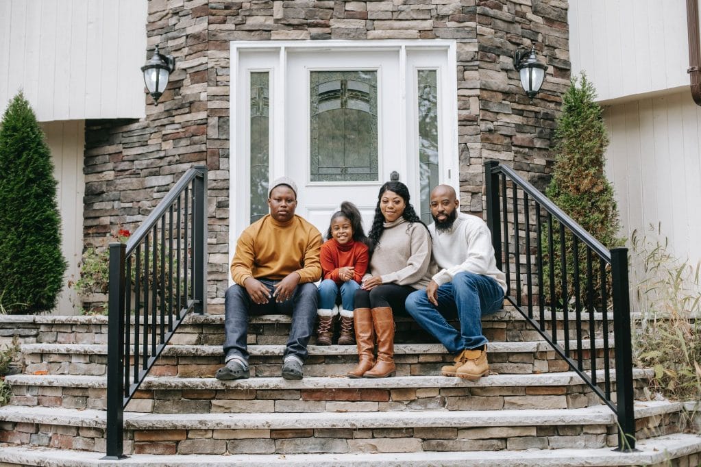 smiling black family on house stairs in daylight