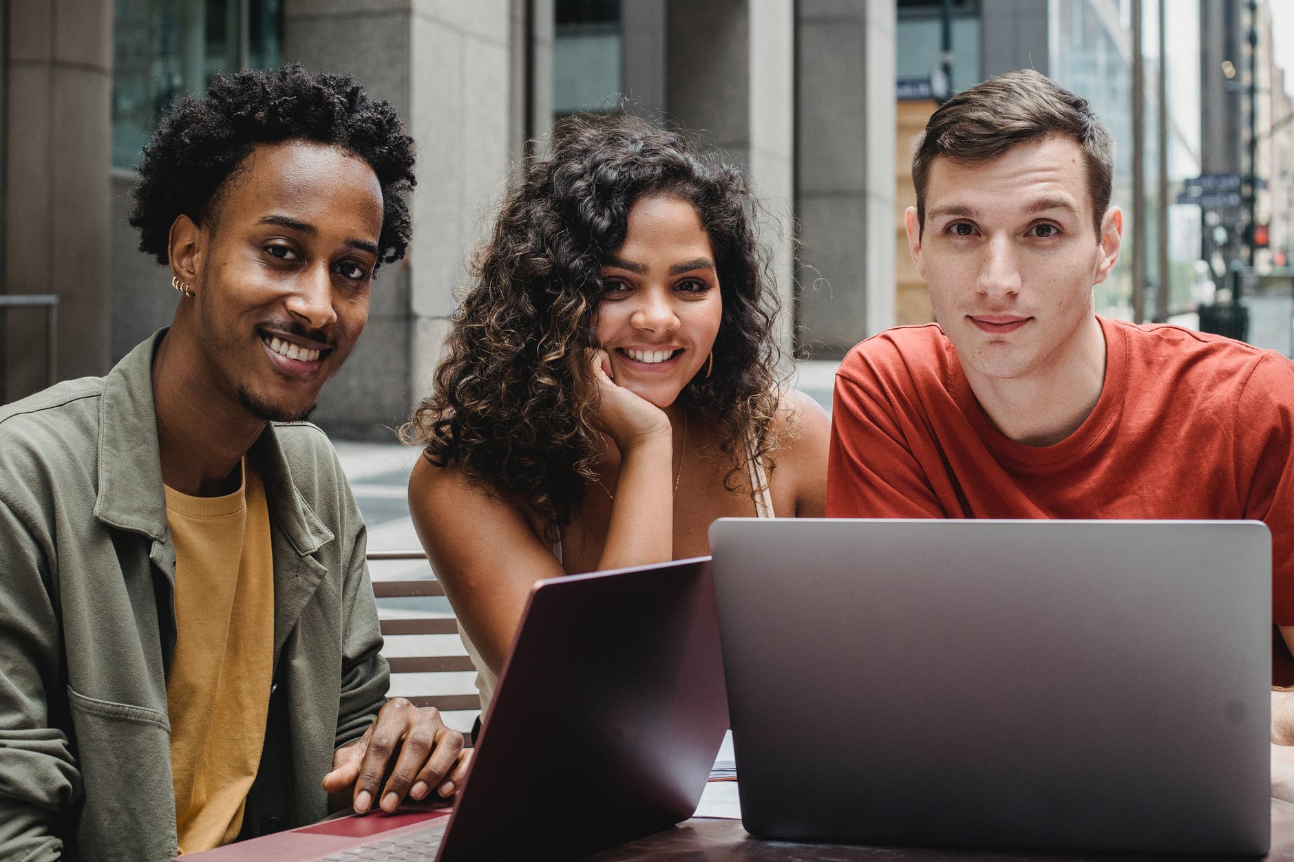 multiracial students working on laptop in street