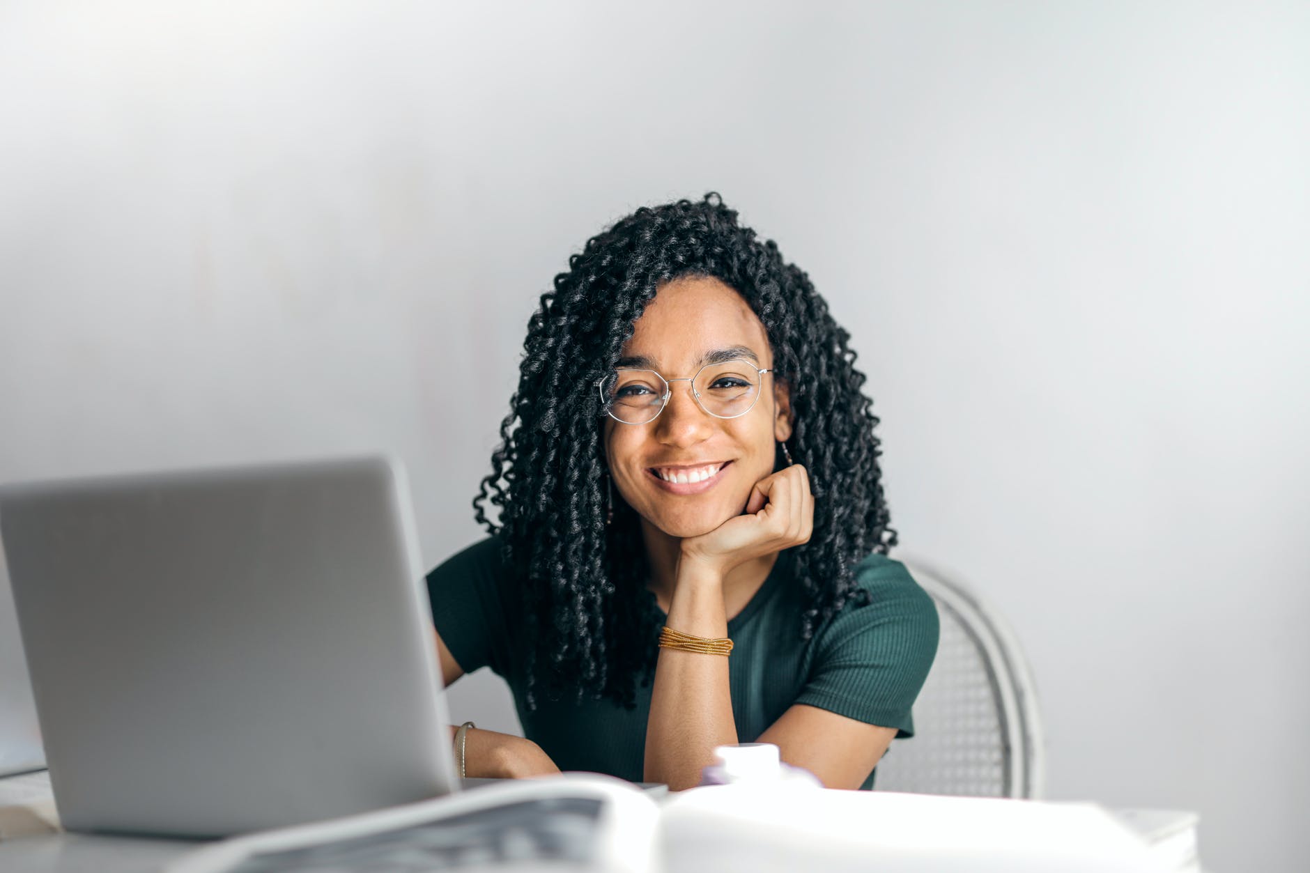 happy ethnic woman sitting at table with laptop smart money bro