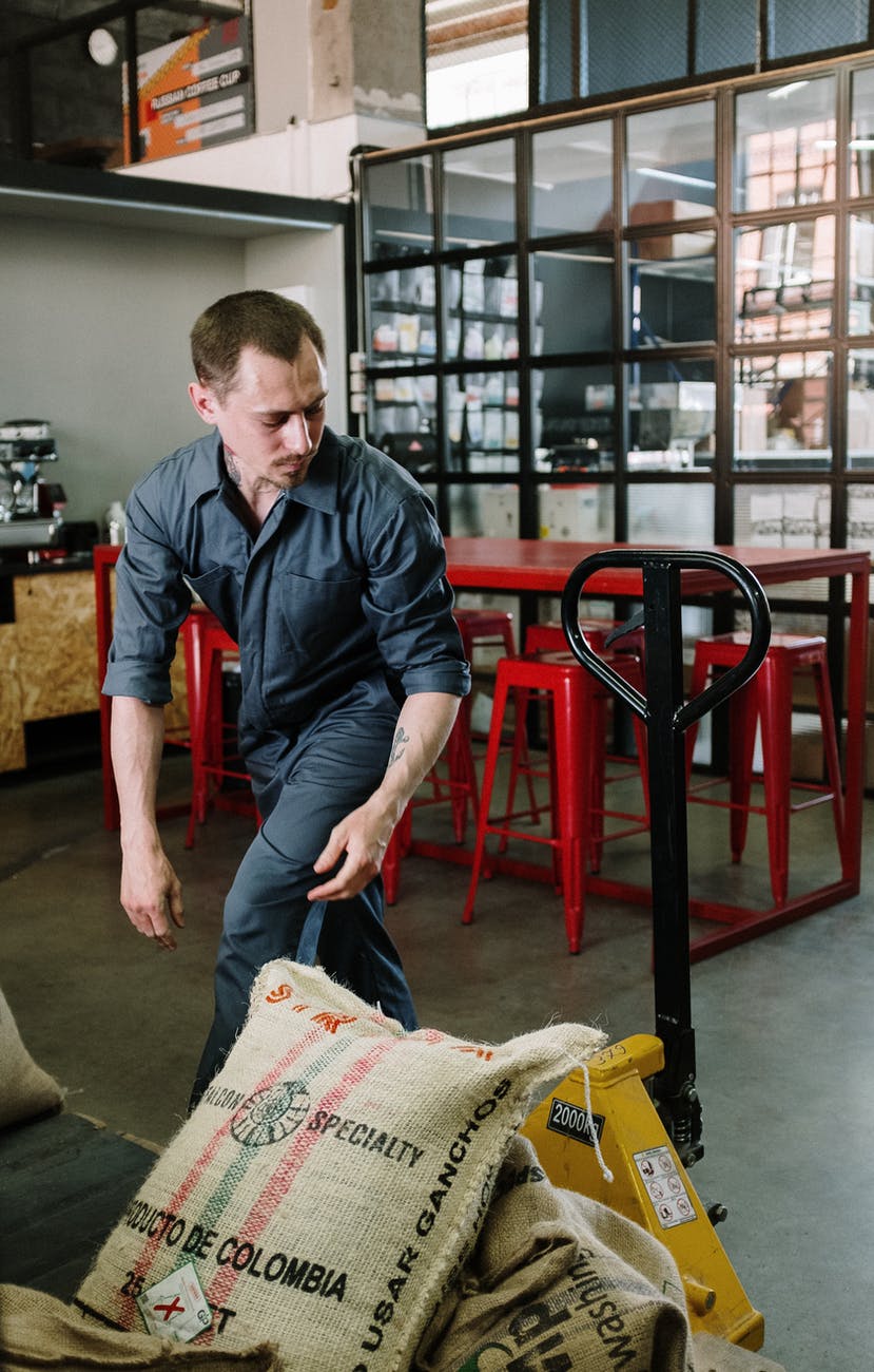 man in blue dress shirt and blue denim jeans sitting on red plastic seat