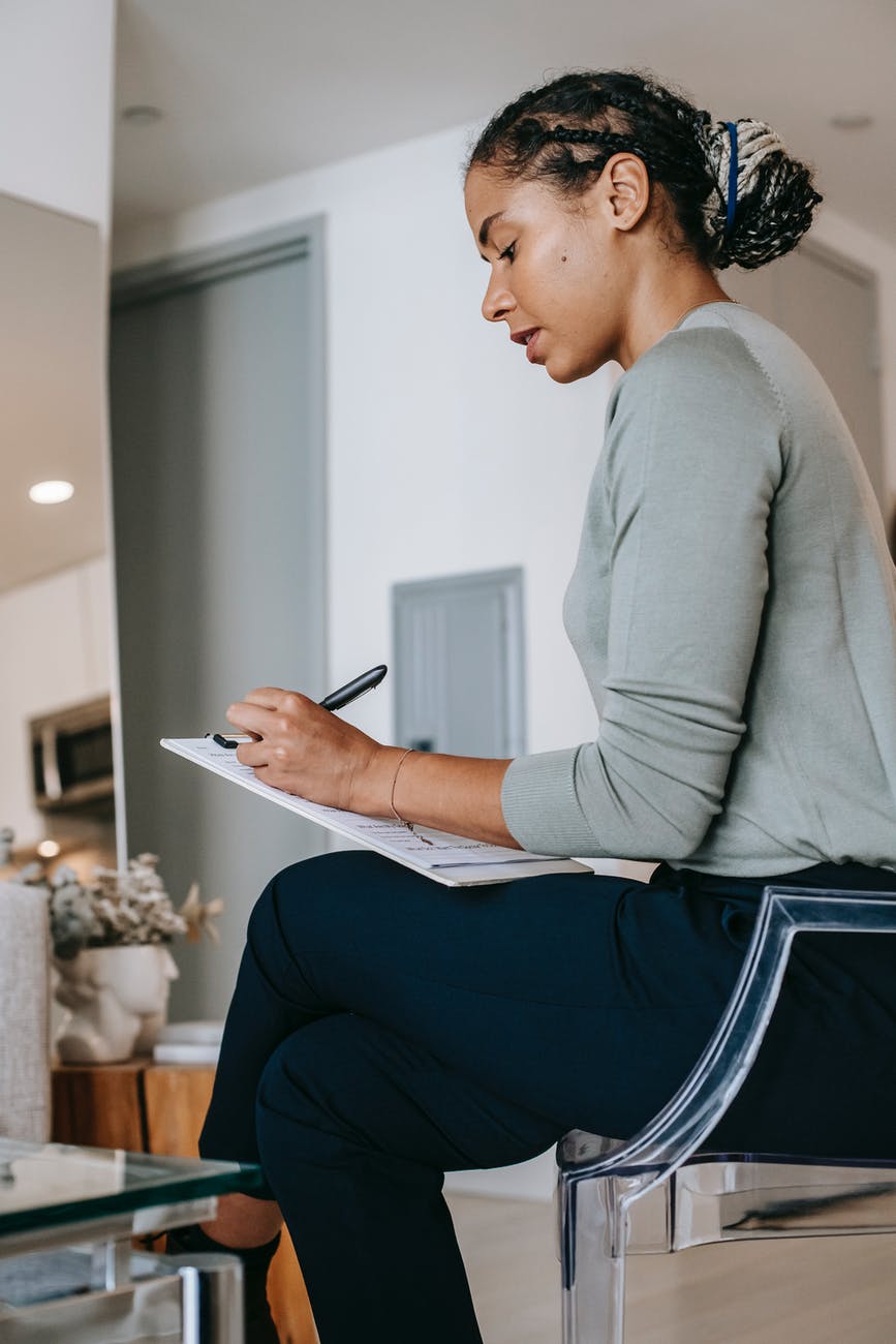 serious black woman taking notes in living room