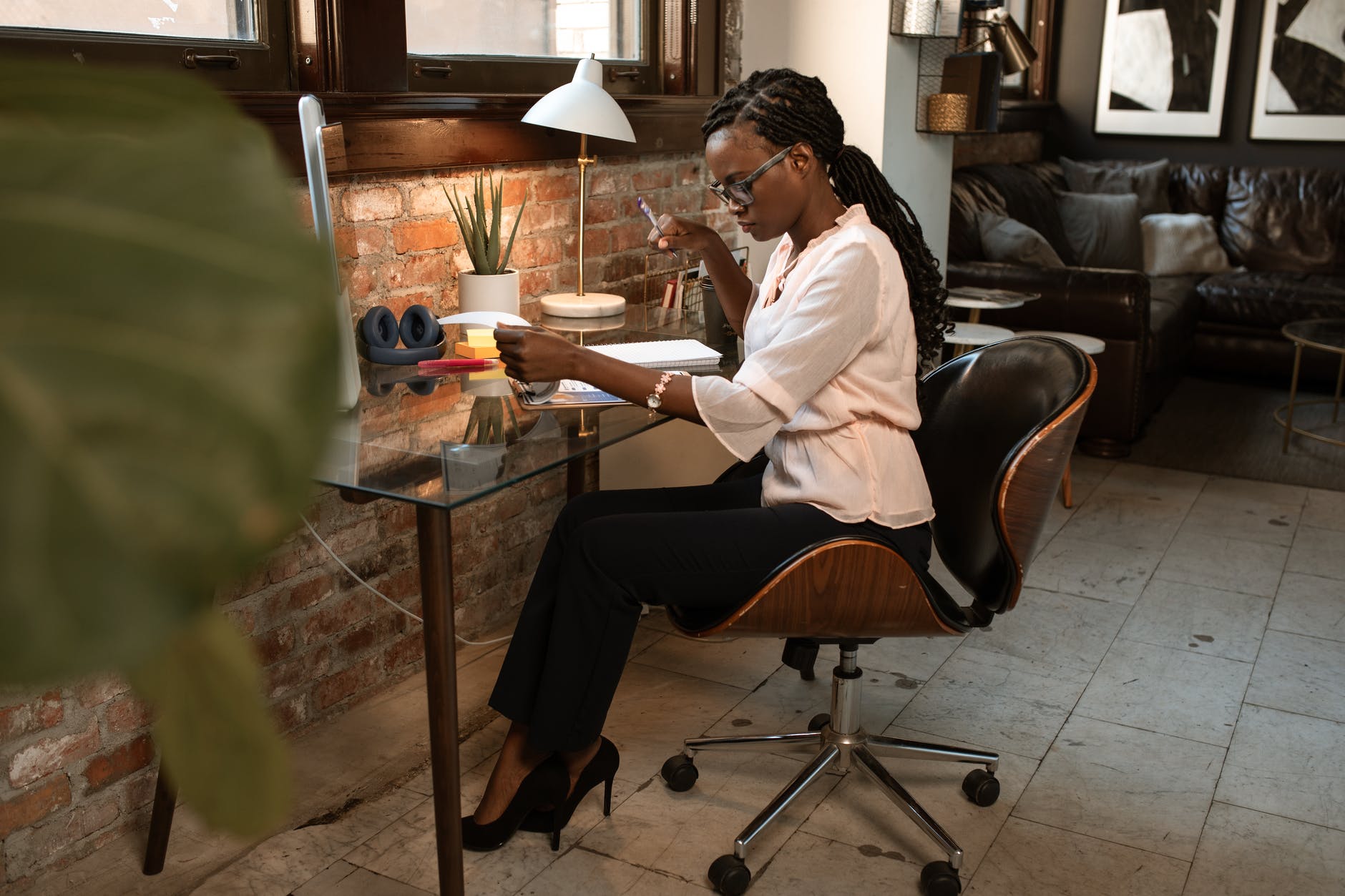woman in white long sleeve shirt and black pants sitting on black leather chair