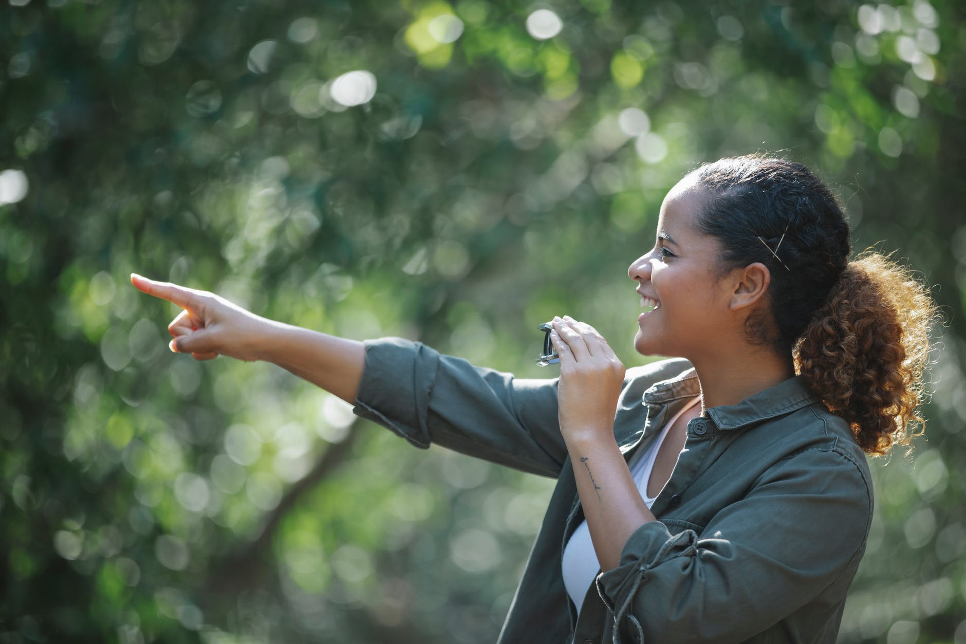 cheerful ethnic woman with binocular pointing away