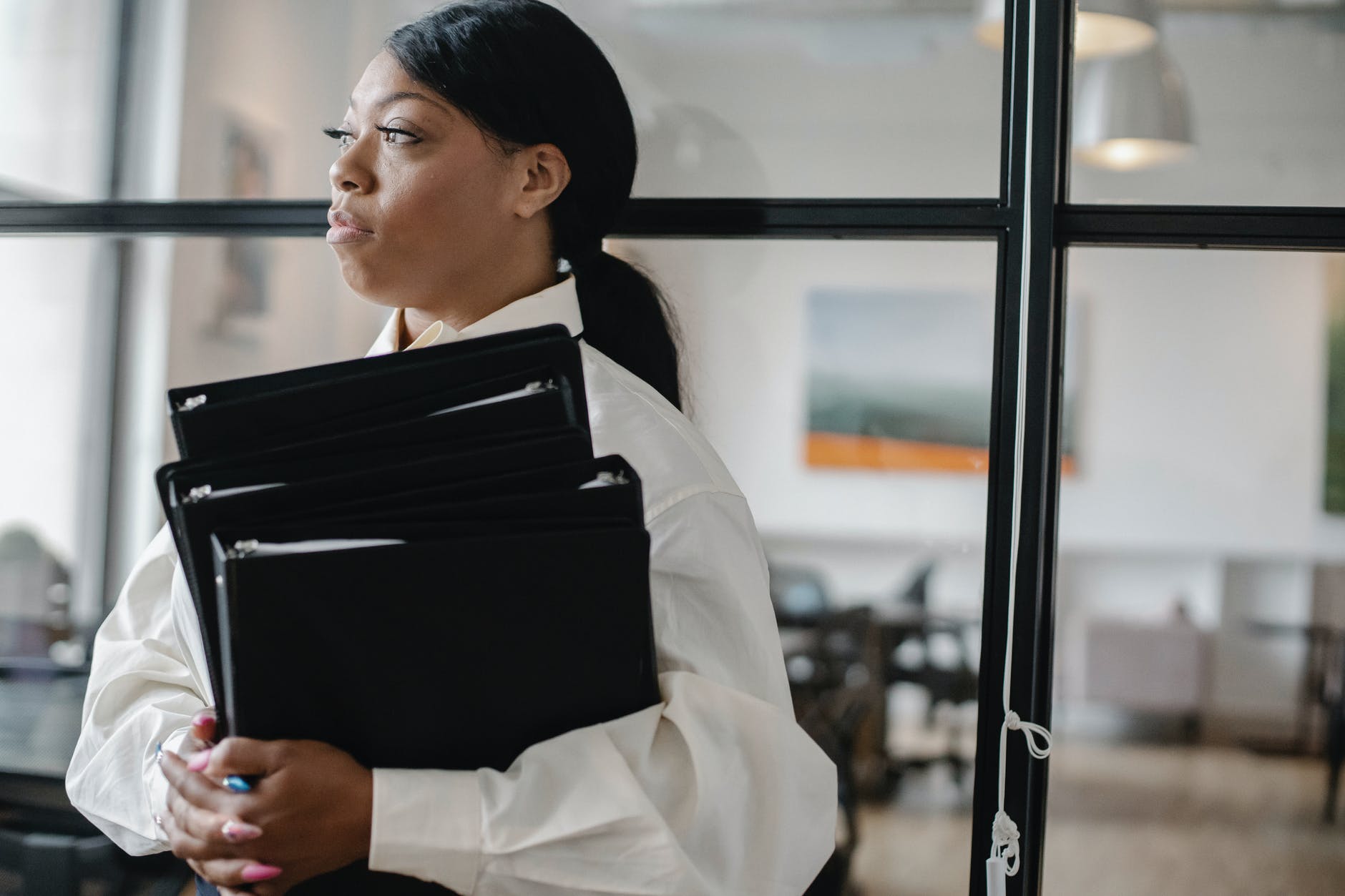 serious black woman carrying documents in office, smart money bro