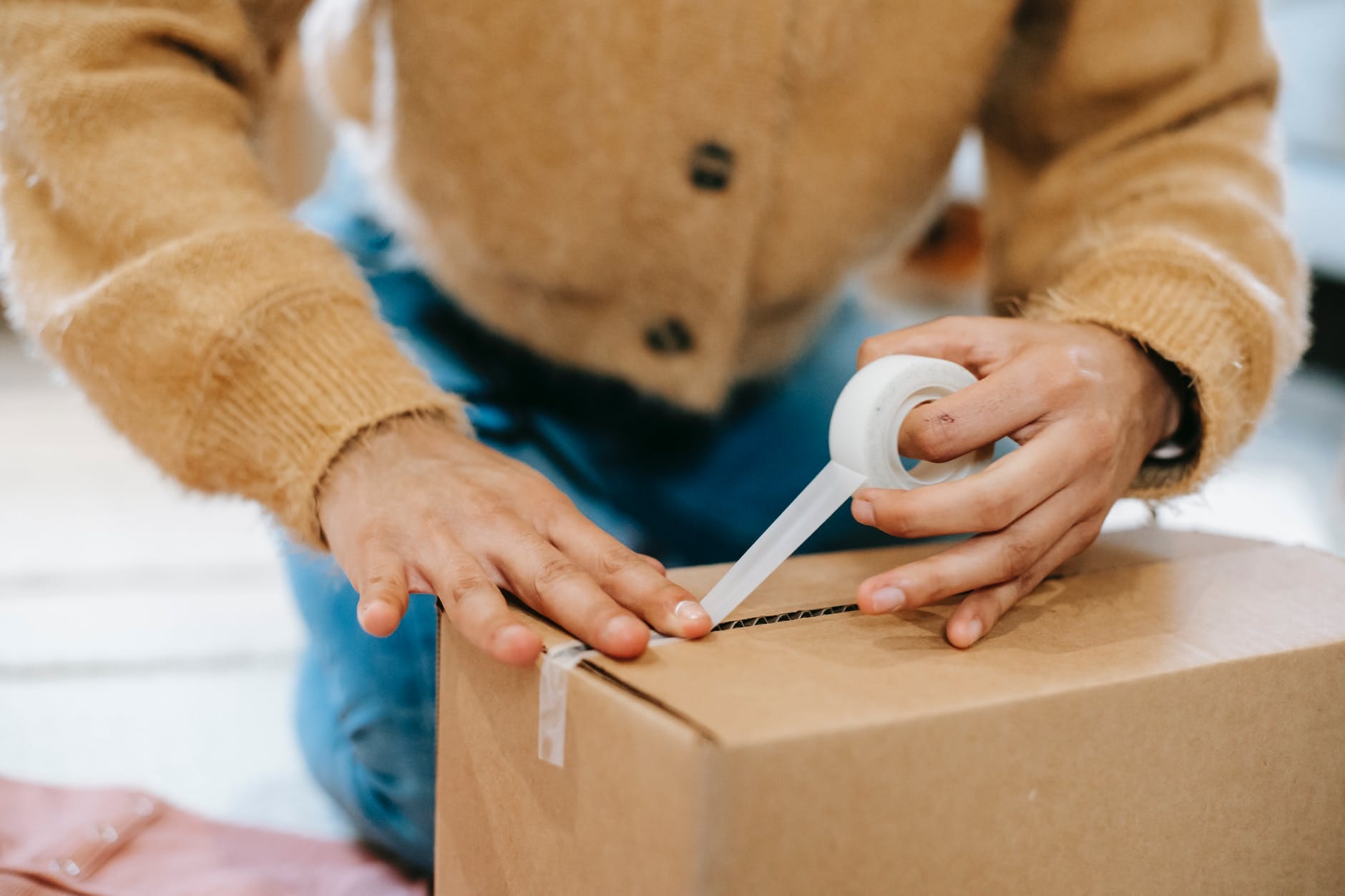 crop unrecognizable woman sealing carton parcel with tape, smart money bro