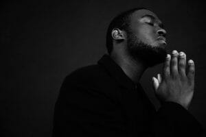black man praying with eyes closed, ways to practice self-care, smart money bro